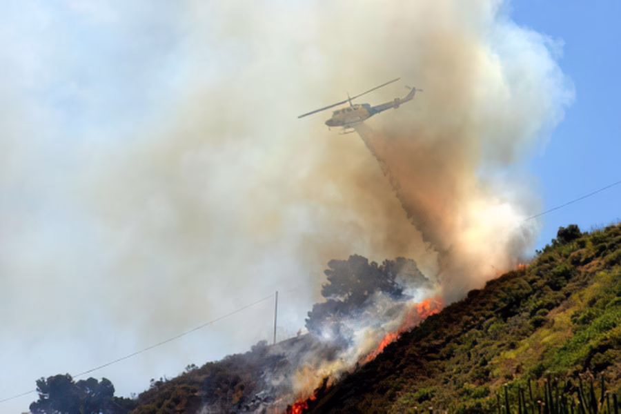 Helicopter dropping fire retardant on a wildfire.